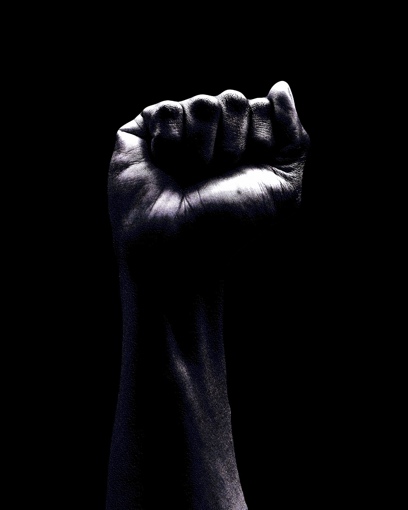 Arm held up, facing us with a closed fist. Black background. Black and white image.