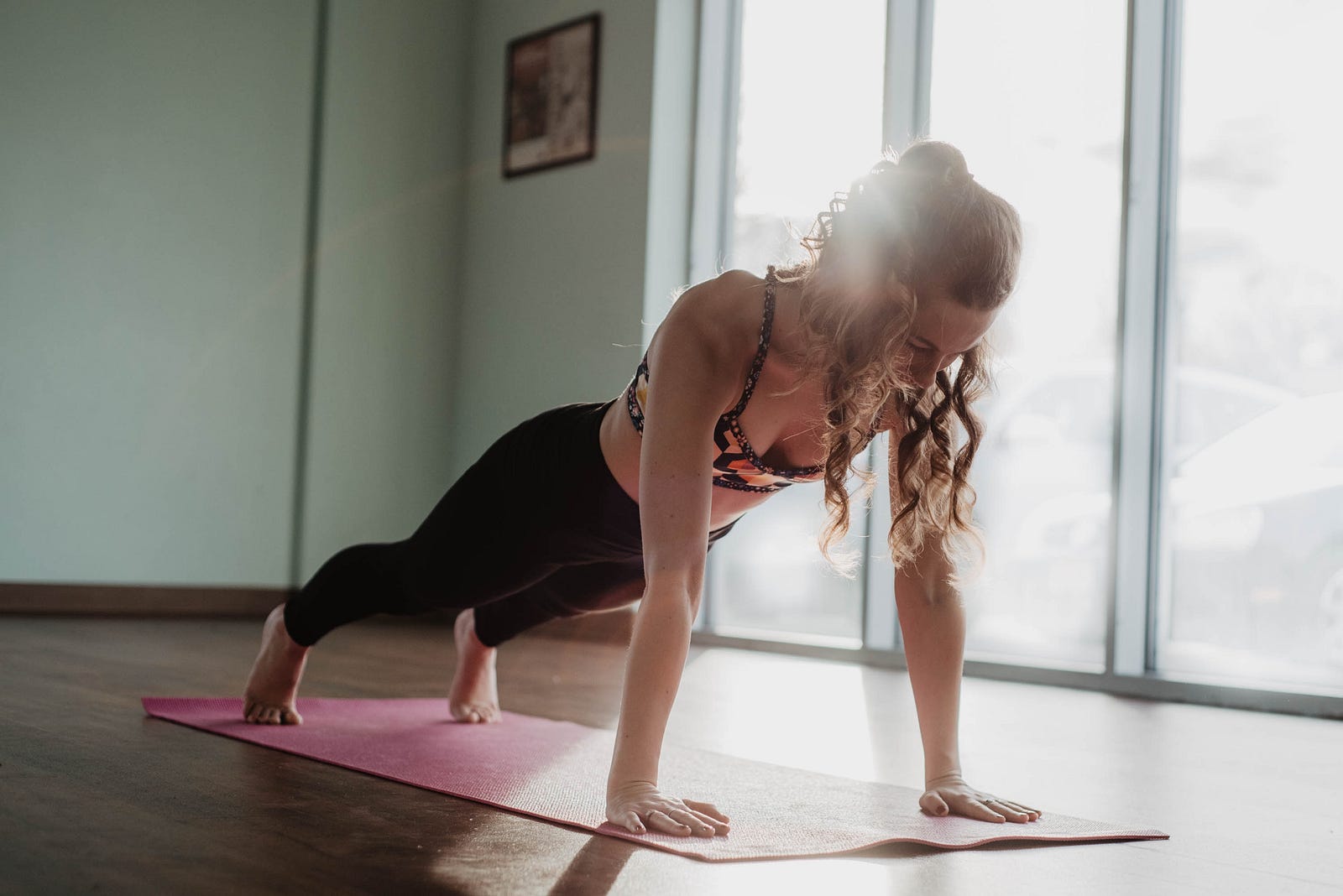 A young white woman does a plank on a pink mat. Incorporating exercises targeting these smaller muscles can enhance your overall fitness and reduce the risk of imbalances and injuries.