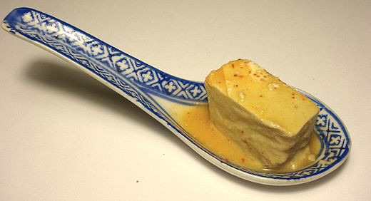 Chinese blue and white spoon holds a single piece of fermented tofu.