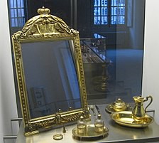 An antique gold-rimed mirror is propped up on the left of the image.