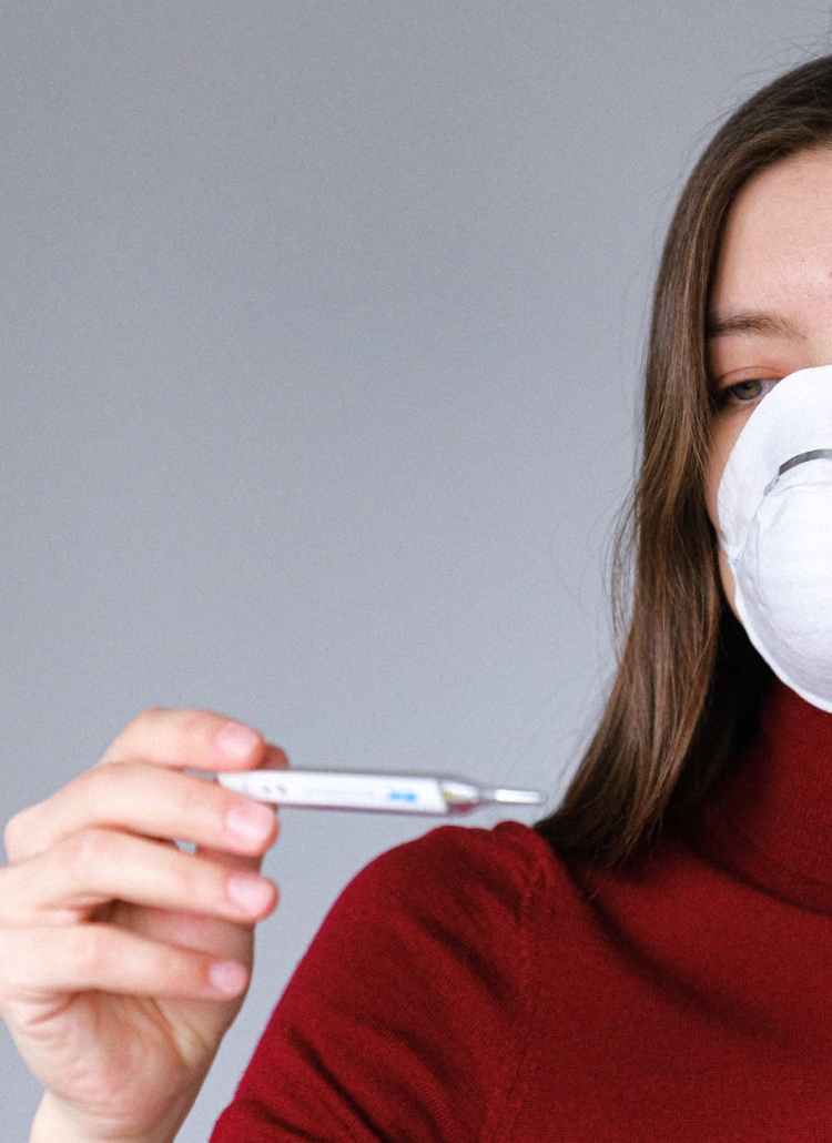 woman in face mask checking thermometer