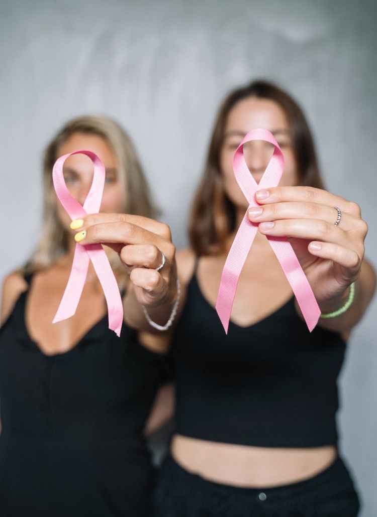 women in black tank top holding pink ribbons