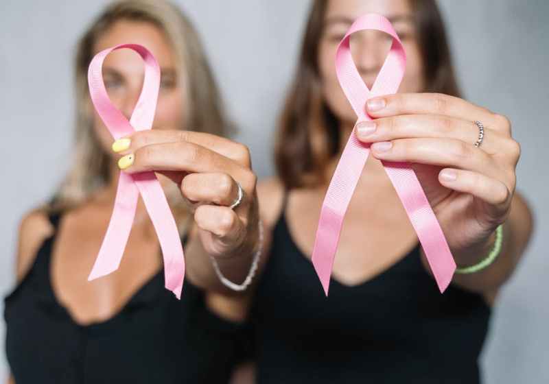 women in black tank top holding pink ribbons