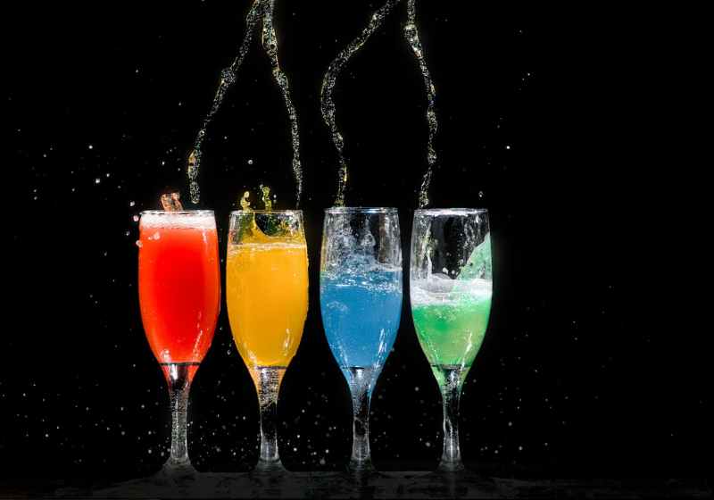 four champagne flutes with assorted color liquids