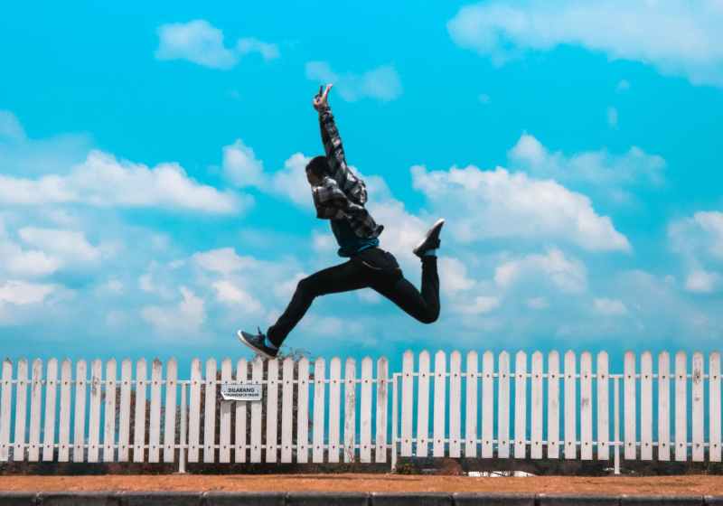 man jumping over white fence