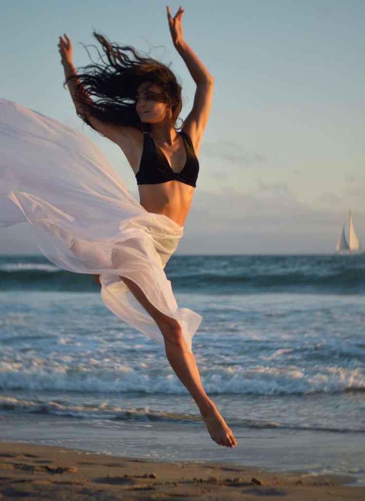 flexible dancer rehearsing on shore of ocean