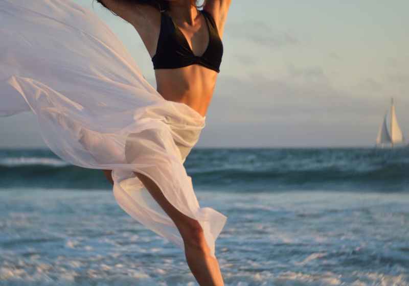 flexible dancer rehearsing on shore of ocean