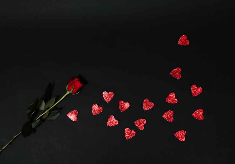 red rose and red heart shapes on black surface