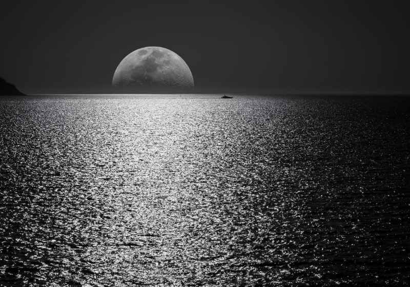 white and black moon with black skies and body of water photography during night time