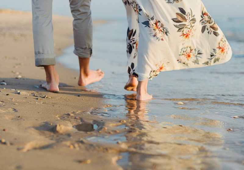 anonymous romantic couple holding hand and walking on sandy seashore