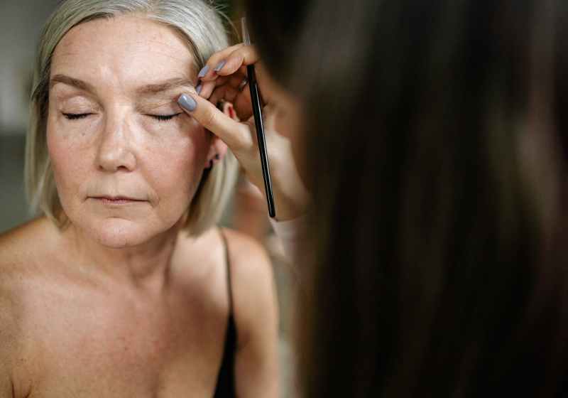 an elderly woman having her makeup done