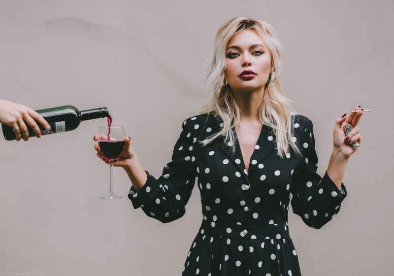 confident woman standing with wineglass and cigarette