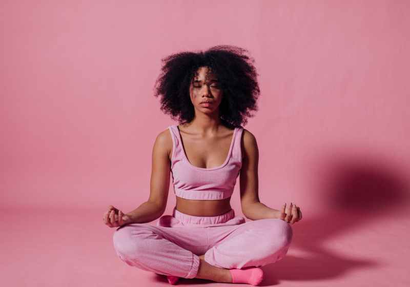 woman in pink crop top and jogging pants practicing yoga