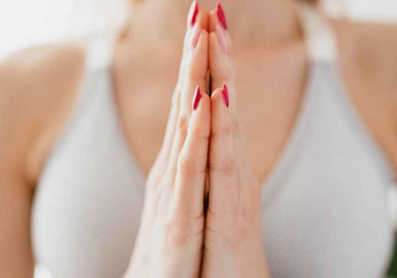 crop calm sportswoman meditating and showing namaste gesture