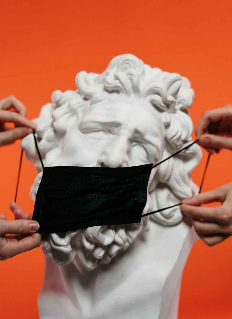 people holding mask over a sculpture