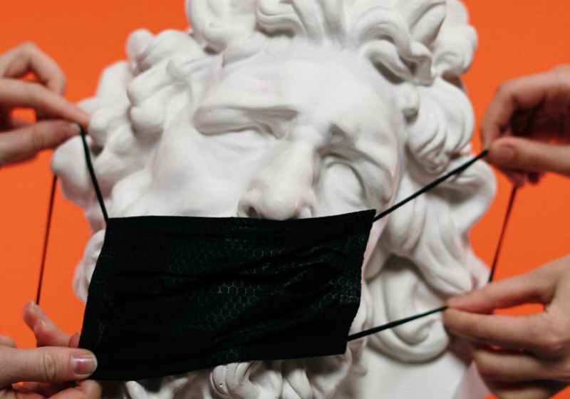 people holding mask over a sculpture