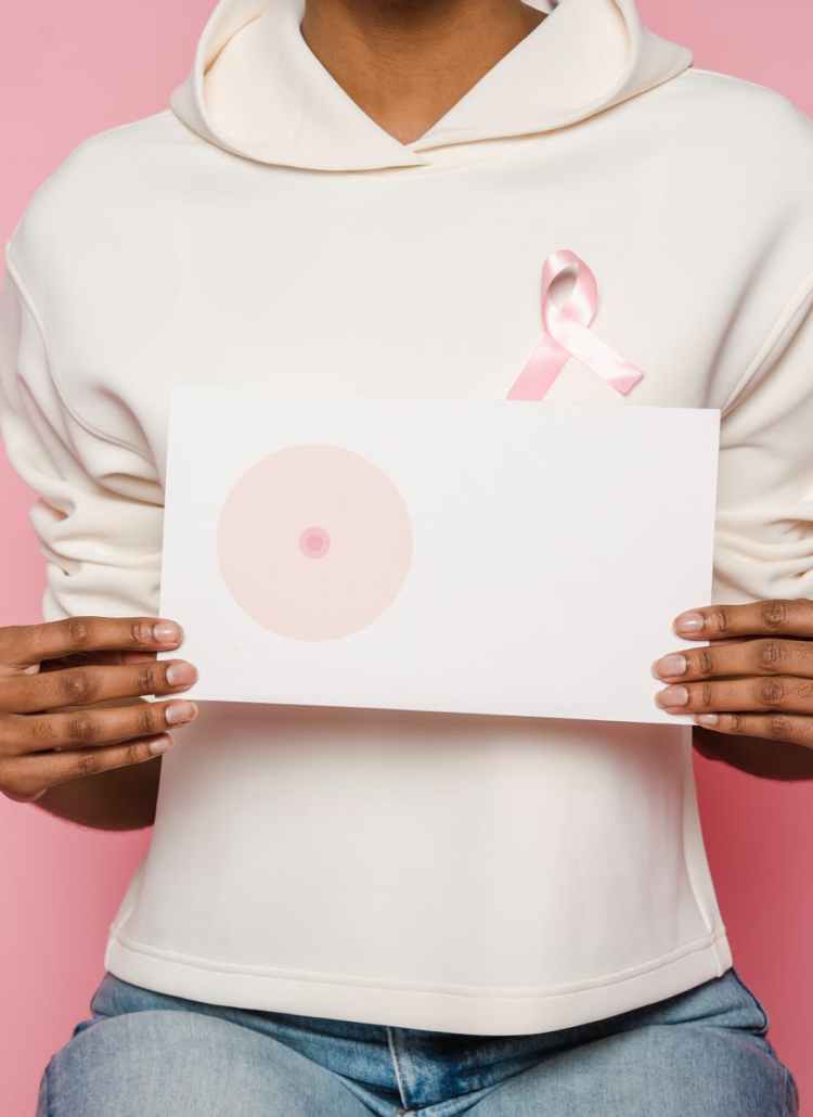black female holding paper with painted one breast as symbol of cancer