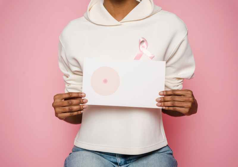 black female holding paper with painted one breast as symbol of cancer