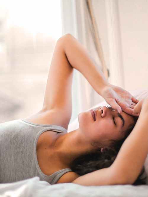 woman in gray tank top lying on bed