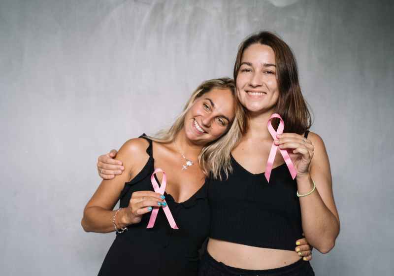 women in black tank top holding pink ribbons