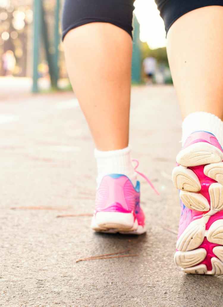 photo of woman wearing pink sports shoes walking