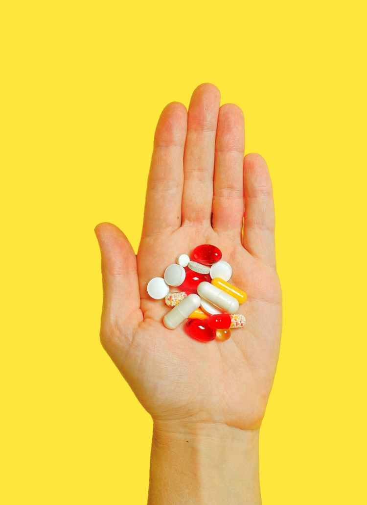 person with bunch medication pills on hand