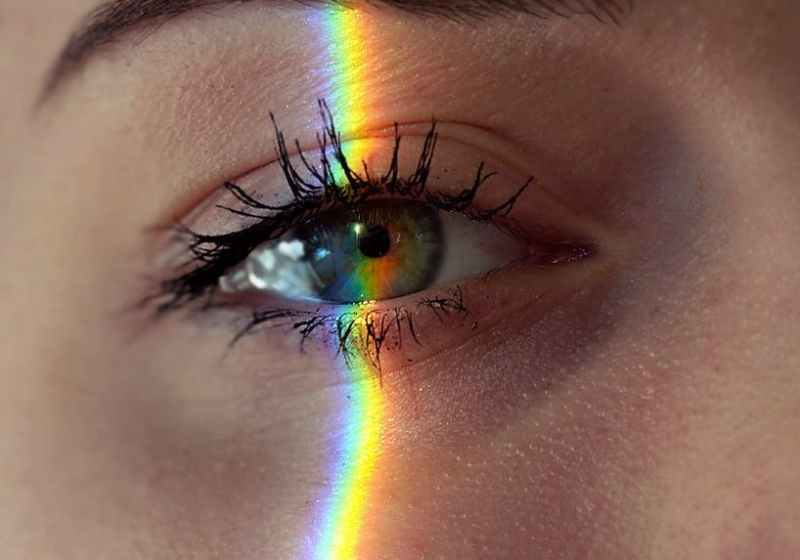 anonymous woman with rainbow light on face