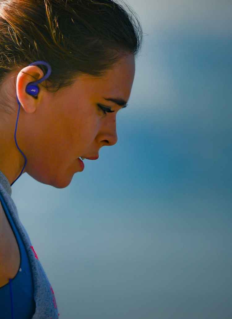 woman wearing smartphone armband and blue earphones