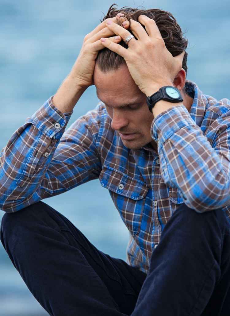 man in blue and brown plaid dress shirt touching his hair