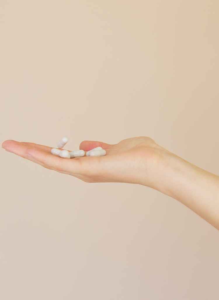 crop female pharmacist with pile of white pills on palm
