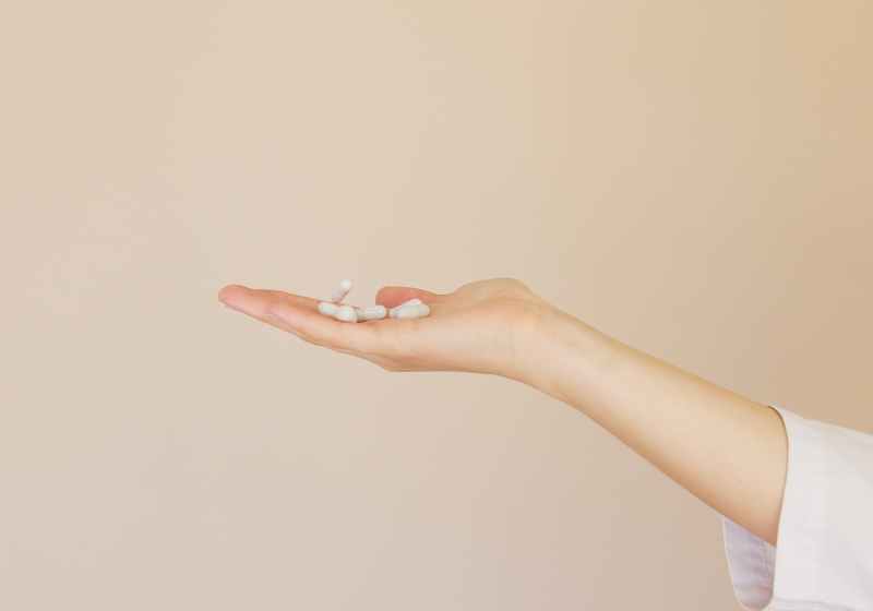 crop female pharmacist with pile of white pills on palm