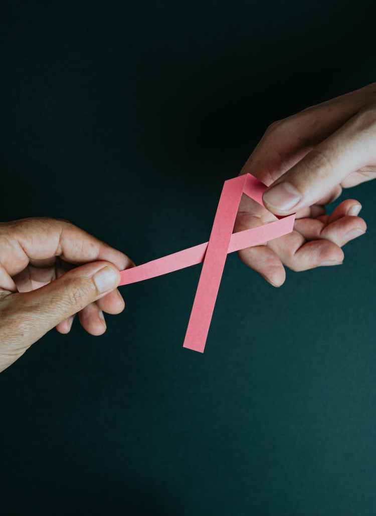 hands holding breast cancer pink paper ribbon