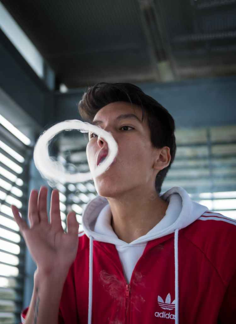 man in red and white hoodie making smoke ring