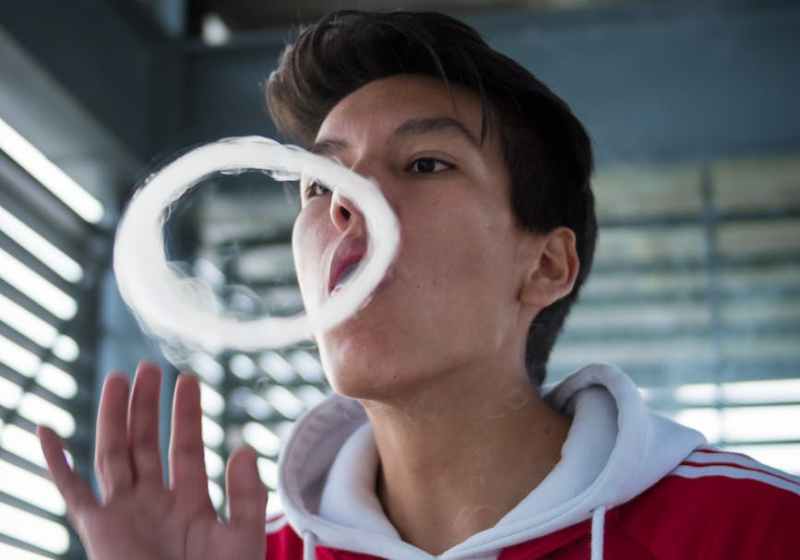 man in red and white hoodie making smoke ring