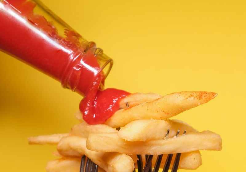 french fries on forks with ketchup near yellow wall