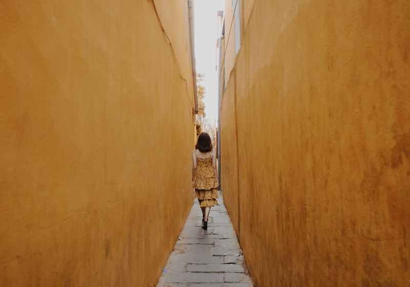 back view of a woman walking in a narrow alley