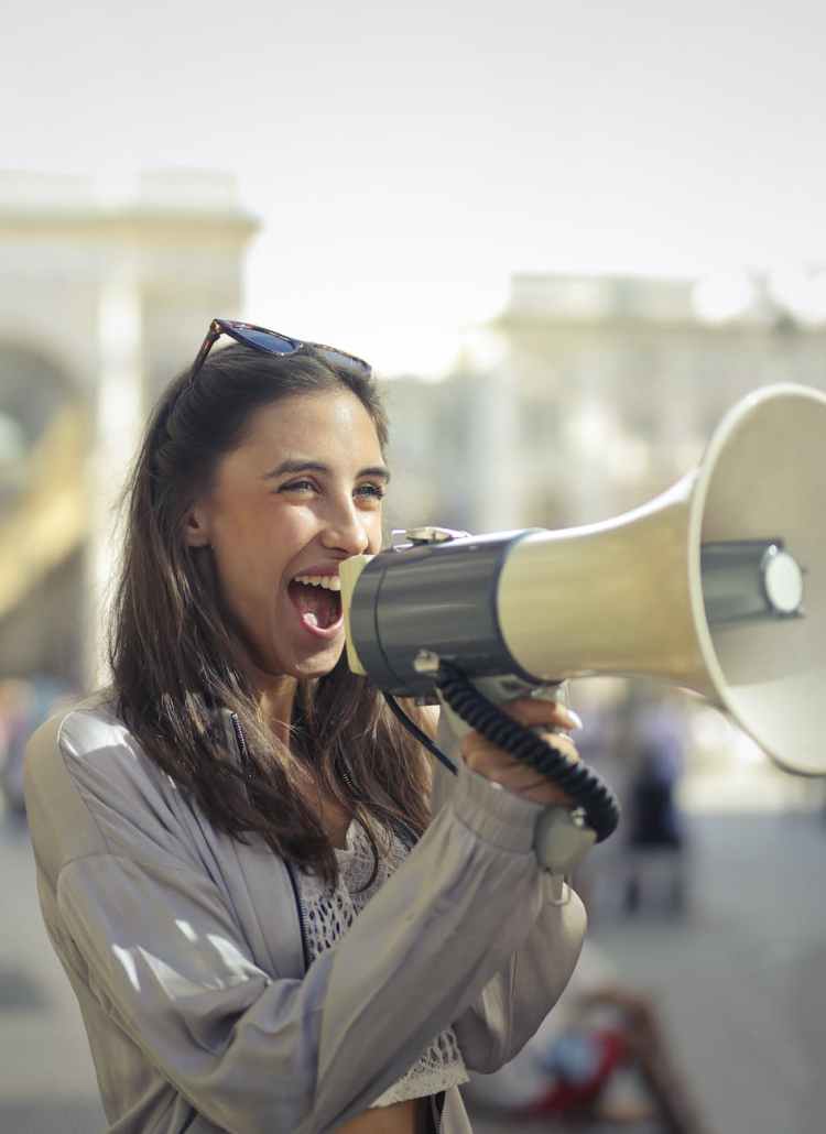 cheerful young woman screaming into megaphone