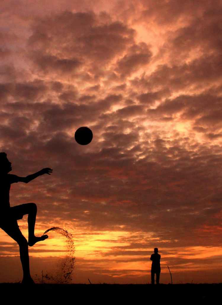 silhouette of a boy playing ball during sunset