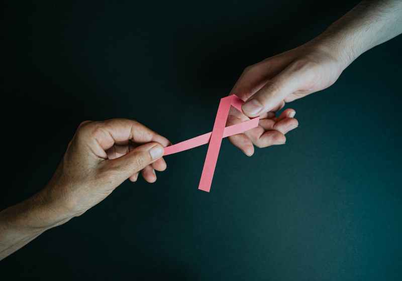 hands holding breast cancer pink paper ribbon