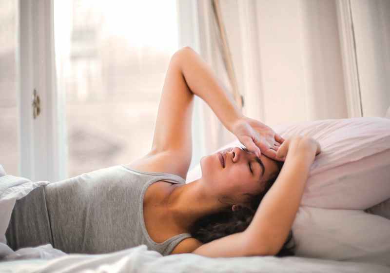 woman in gray tank top lying on bed