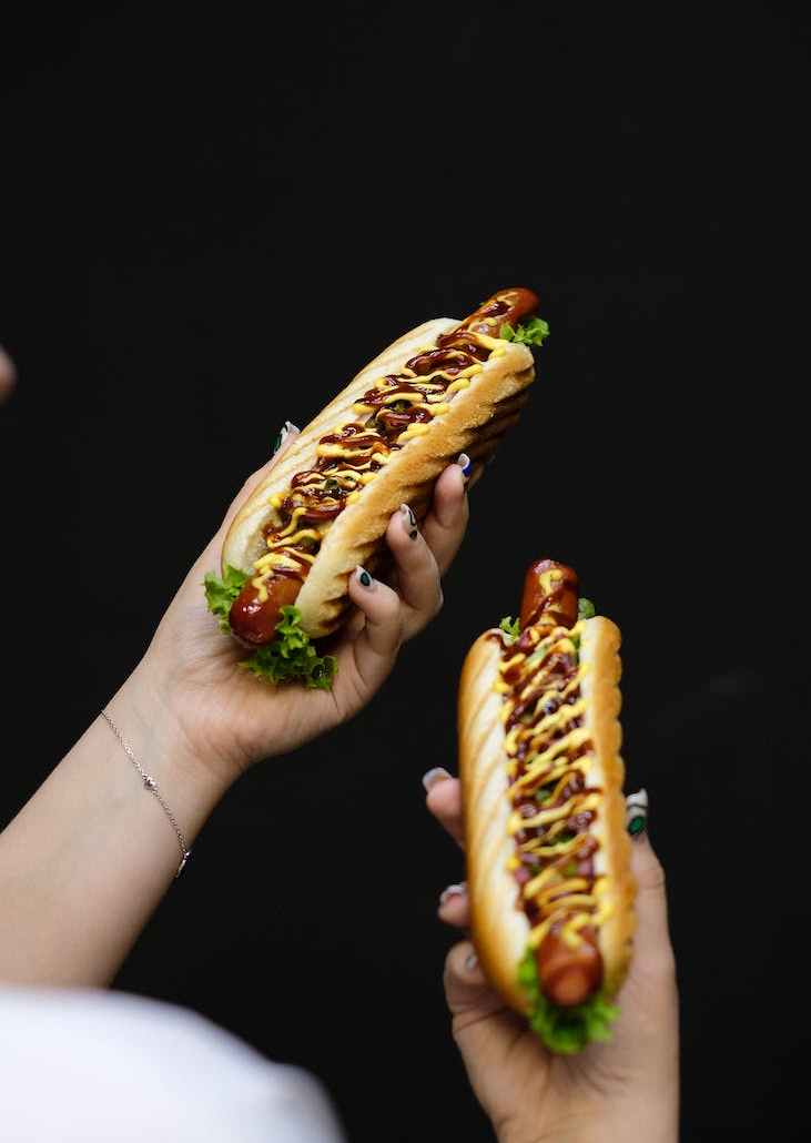 person holding hot dog sandwiches