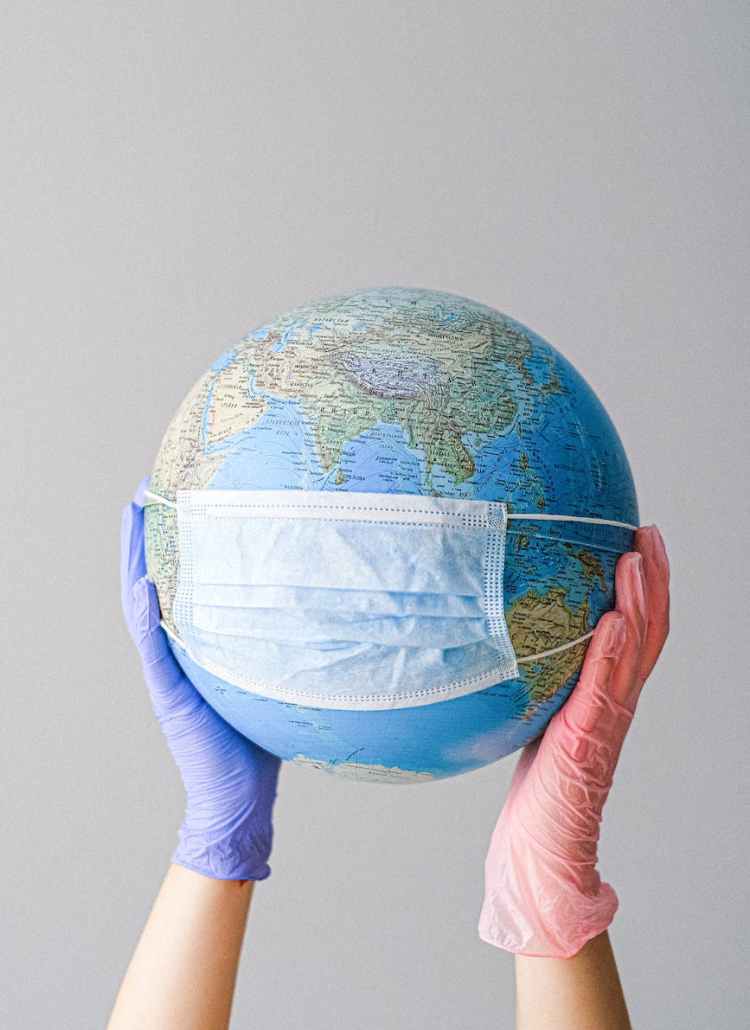 hands with latex gloves holding a globe with a face mask