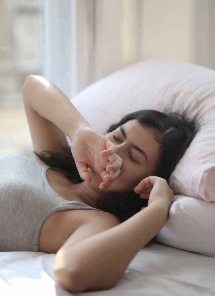 woman in gray tank top lying on bed