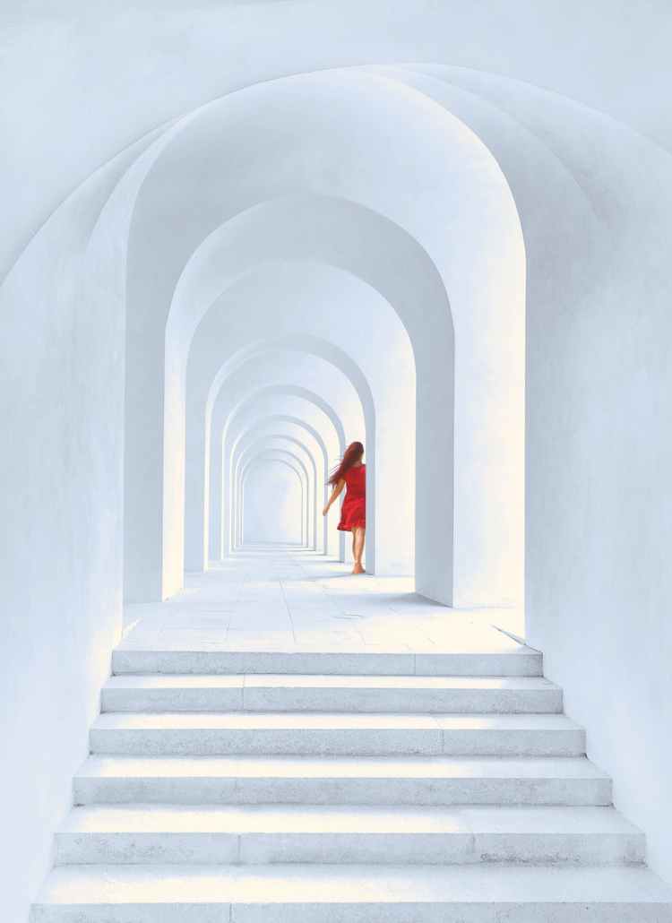 woman in red dress standing in white arch building