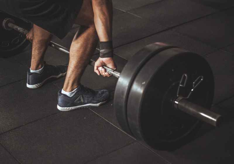 man in black reebok shoes about to carry barbell