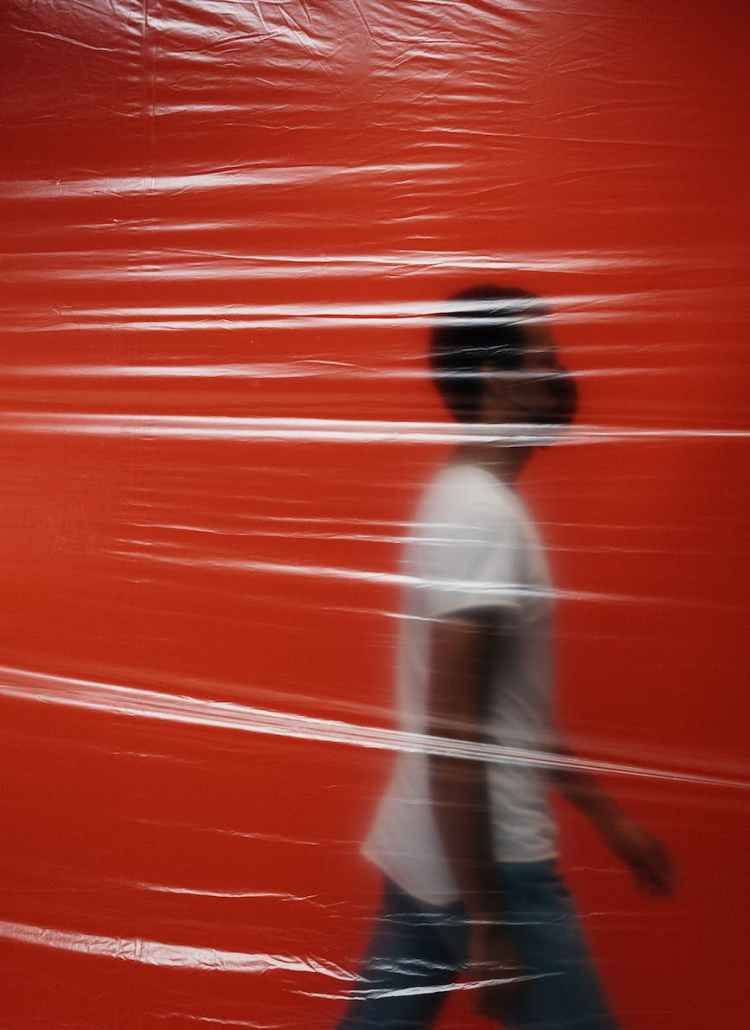man walking in a room behind a plastic
