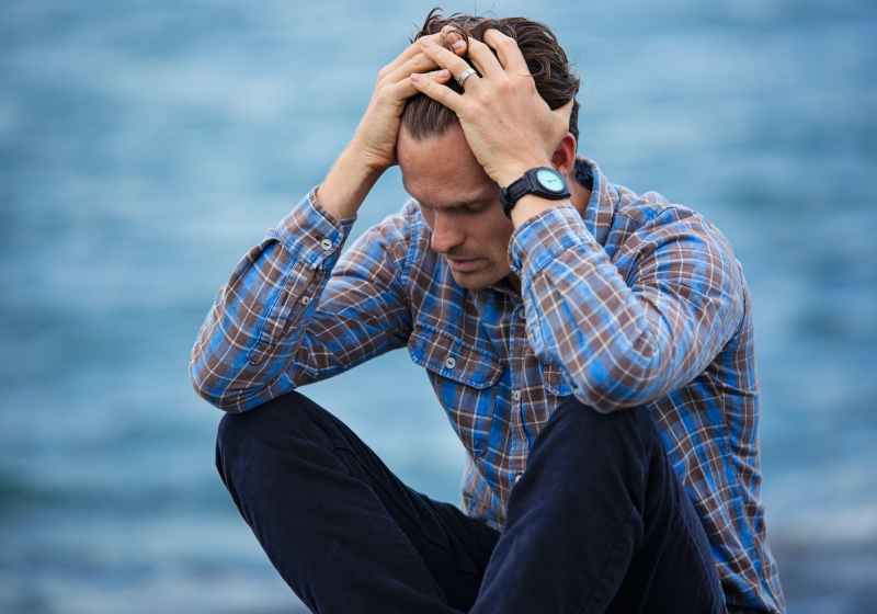 man in blue and brown plaid dress shirt touching his hair