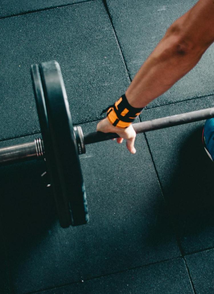 person wearing black shorts and blue lace up low top sneaker holding black barbell