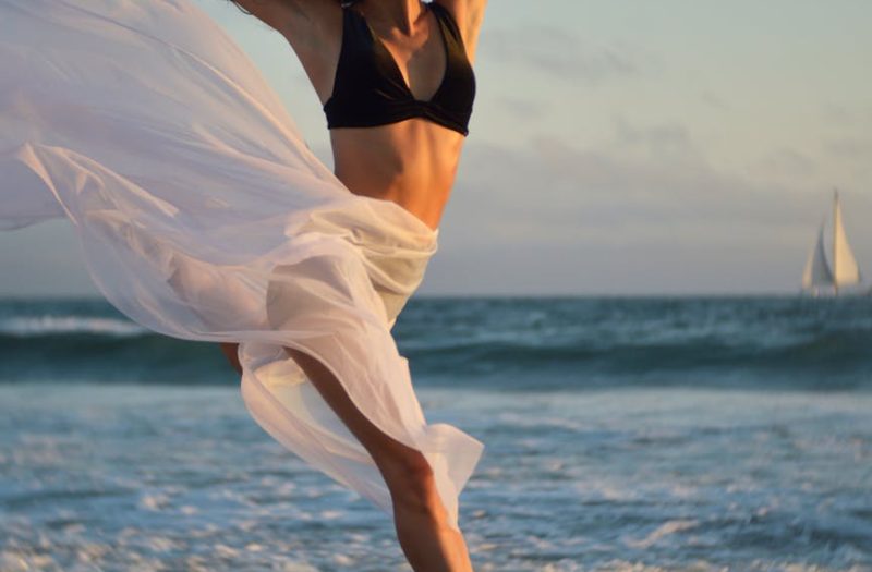 flexible dancer rehearsing on shore of ocean