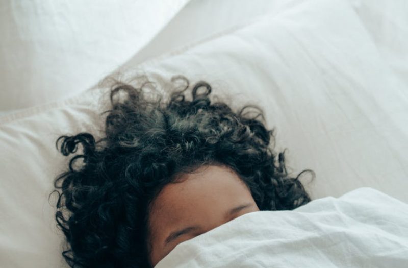 unrecognizable person sleeping under blanket